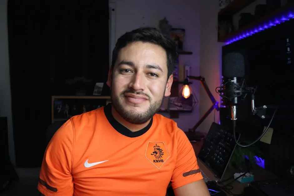 Portrait of a smiling man in a home studio setup with a microphone, showcasing creativity and comfort.