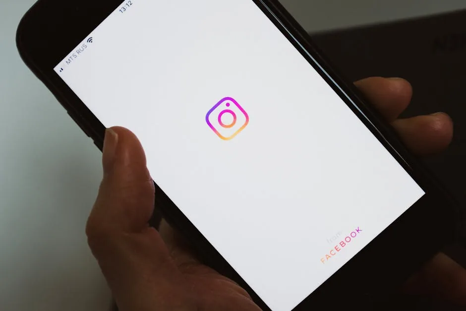 Crop faceless person taking mobile phone and demonstrating blank screen with social media app logo while having break and surfing internet